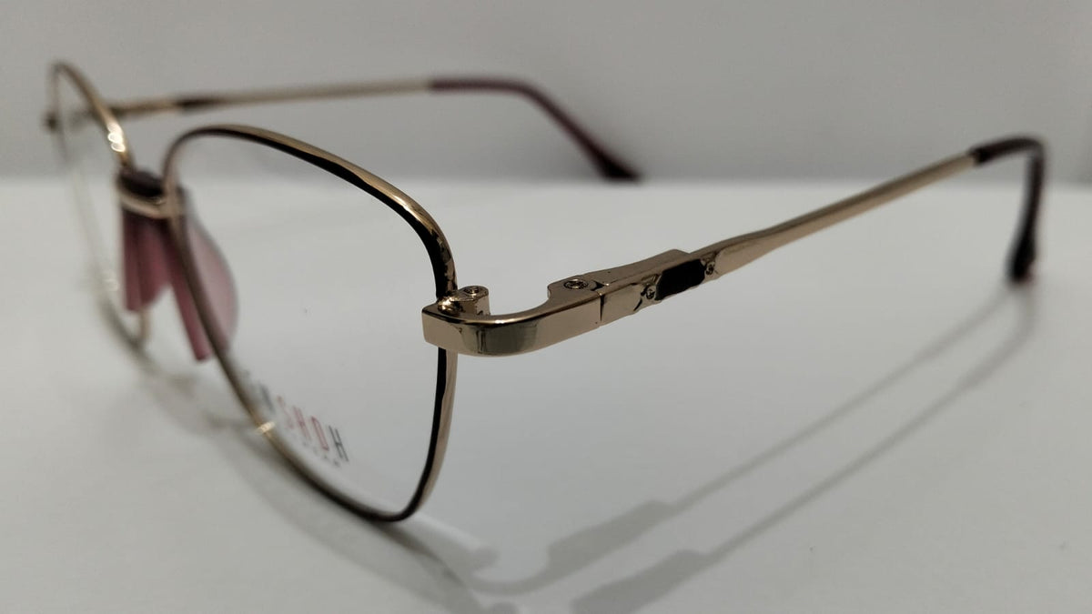 Angled side view of gold-tone metal eyeglasses with burgundy temple tips