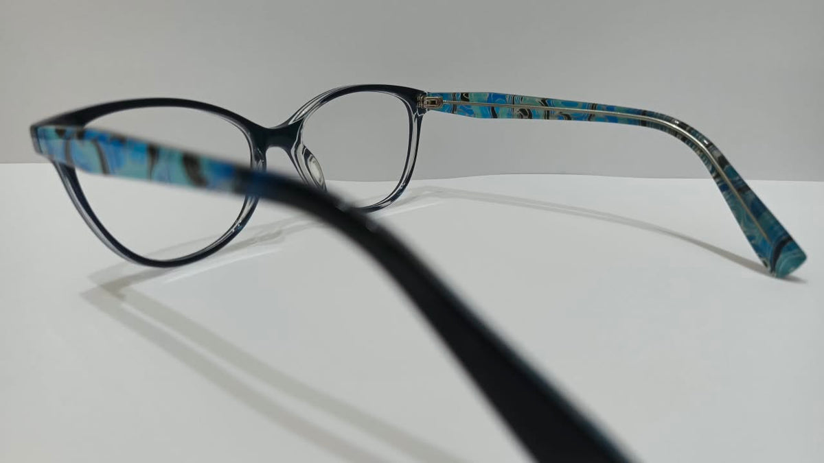 Three-quarter view of black cat-eye eyeglass frames with blue patterned temples