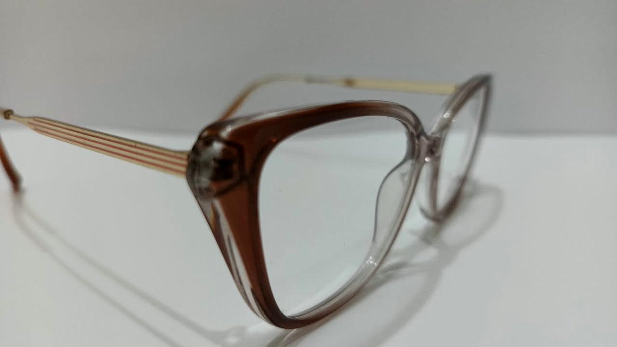 Angled close-up of the brown eyeglass frame and striped gold-tone temple